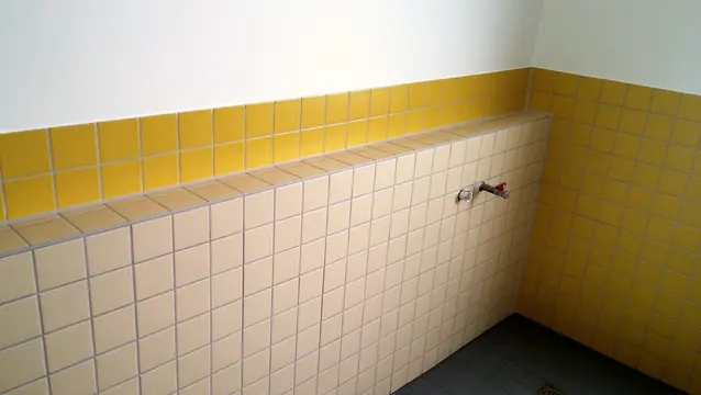 Gelbe Wandfliesen über einer hellen, gefliesten Vorwand mit Ablage