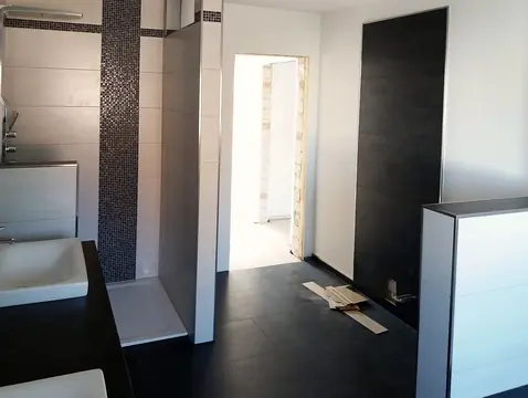 Bad mit Mosaikband an der Dusche und dunklem Boden