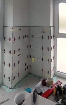 Helle Wandfliesen mit Nivellierhilfen neben einem Fenster