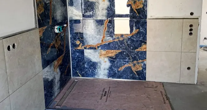 Dusche mit blauer Dekorwand, seitlich helle Wandfliesen