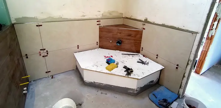 Eckbadewanne im Rohbau, zwischen den Fliesen Nivellierhilfen